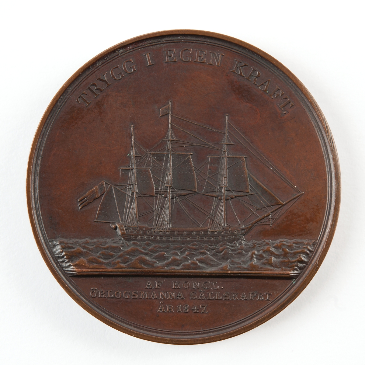 Åtsidan: Bröstbild av O. G. Nordenskjöld i mantelveck
Frånsidan: Ett linjeskepp under segel på havet.