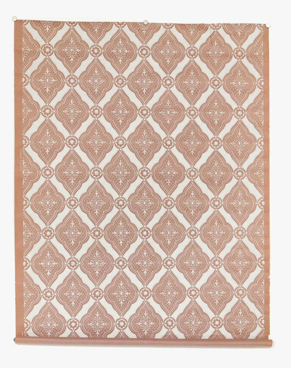 Tapetrullar, två st. av tunnt sprött papper i gråaktig blåröd färg med tryckt vitt mönster med oregelbundna fyrpass och stjärnor.
