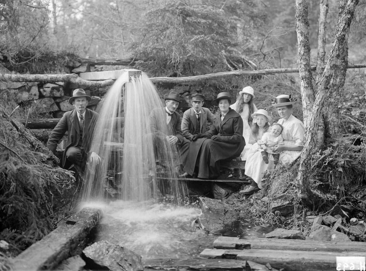 Sammankomst invid Susehål i Svinhults socken 1921. Duschanordningen i Susehålsbäcken är byggd av målaren Henning Hörberg till vänster i bild. Längst till höger ses Hennings hustru Signe med parets dotter Anna-Stina i knäet. Övriga personer är syskonen Karl Ax och Amanda Ax med Amandas son Ragnar dem emellan. Vid tiden var de boende i missionshuset Jennylund där Karl var vaktmästare. Den stående flickan heter Ingrid Johansson och är dotter till barnmorskan Sofia Johansson i Lilla Bona, född Ljungberg och änka sedan 1912. Den sittande flickan är Karl Ax dotter Anna Ax.
