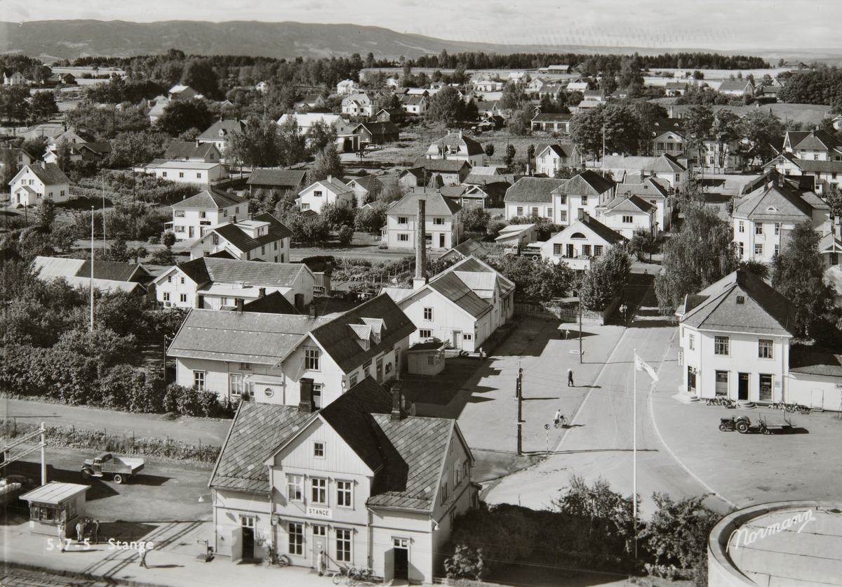 Postkort, Stange sentrum, Stangebyen, Stange stasjon i forgrunnen, forretninger langs Storgata, sett fra kornsiloen,