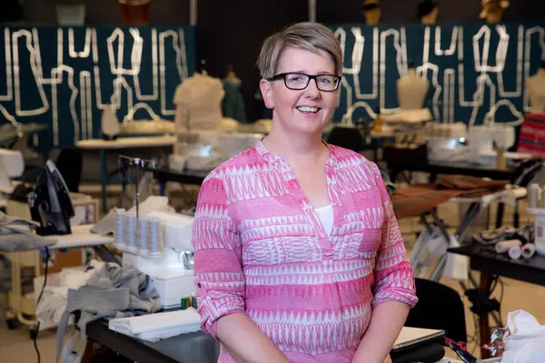 Veronika Møgster som står framfor mange symaskiner. Bilde er tatt på symesterskapet i 2021.