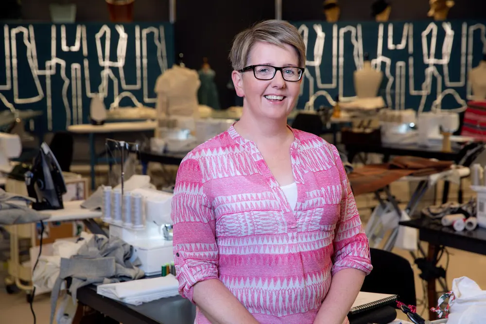 Veronika Møgster som står framfor mange symaskiner. Bilde er tatt på symesterskapet i 2021.