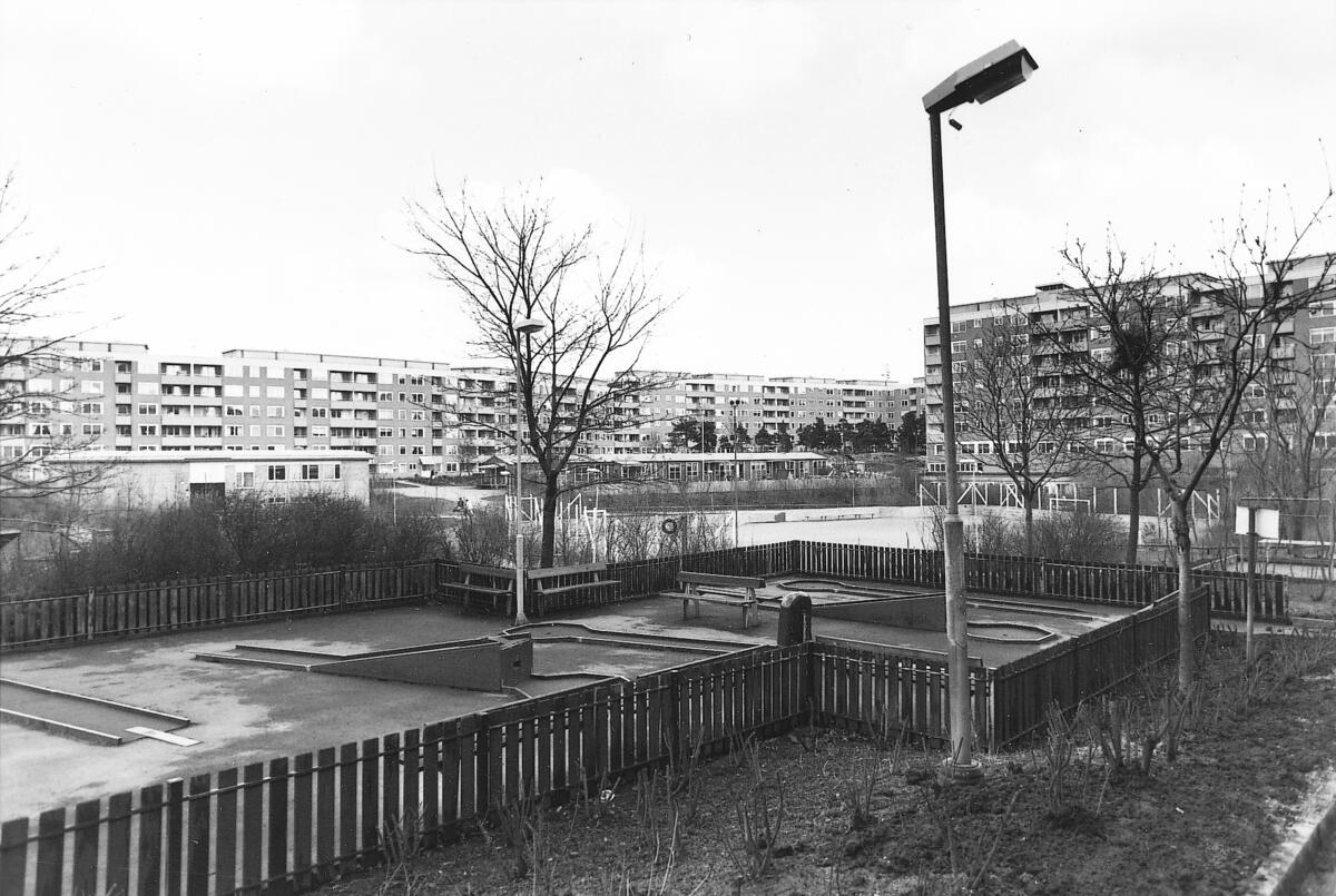 Husen på Henriksdalsberget - ritade av arkitekterna Erik och Tore Ahlsén - uppfördes åren 1967-1971 och inrymmer 770 lägenheter byggda kring en bilfri gård. Minigolfbanan i förgrunden är numera borta, liksom skolan, biblioteket, läkarmottagningen och postkontoret. Foto 1992.