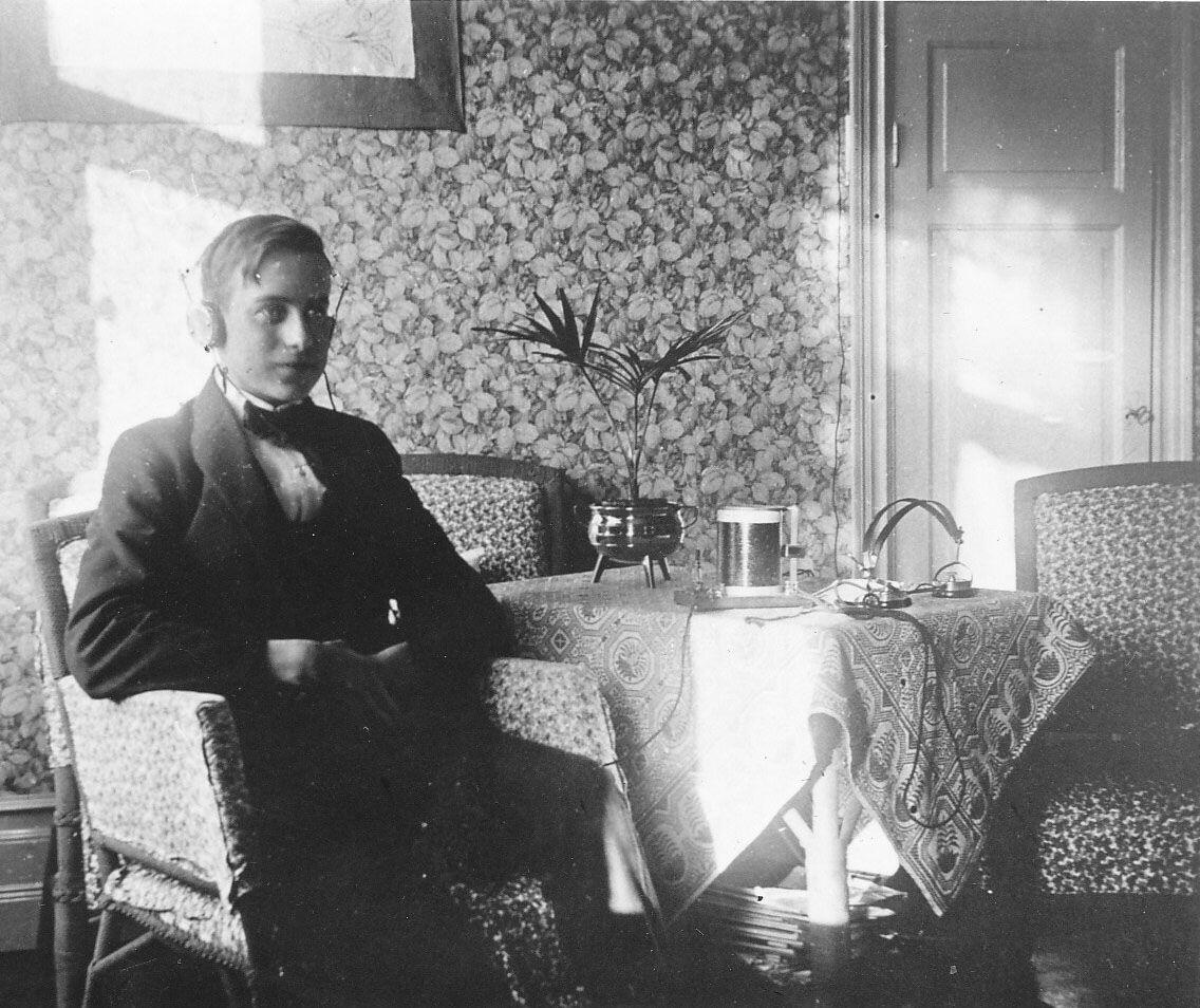 Interiör från Villa Birka - uppförd 1903 - på Birkavägen 12. Notera att den unge mannen förmodligen lyssnar på radio med hjälp av hörlurar. Foto 1924.
