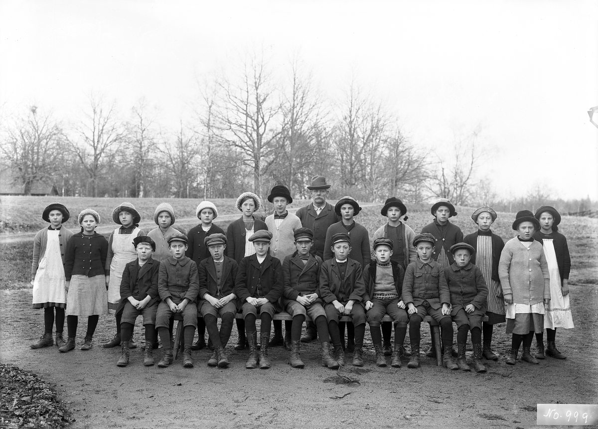 Kantor Bernhard Hultgren med skolklass intill Svinhults kyrkskola läsåret 1915/16. Bland barn som identifierats ses Maria Pamp, Anny Ax och Emil Hultgren. Maria och Anny står som fjärde respektive sjätte flicka från vänster. Emil ses sittande längst till höger. Bernhard var upplysningsvis bror till fotografen.