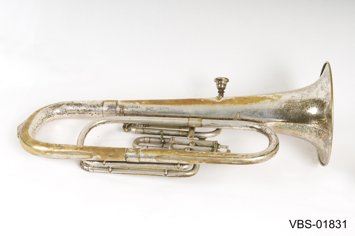 Blåseinstrument i forsølvning messing med tre ventiler. 
Tubaen har et etui tilpasset formen, med et håndtak. Instrument etuiet er foret på innsiden med et mørkeblått ullbelegg, og dekket utenpå med svart kunstlær.