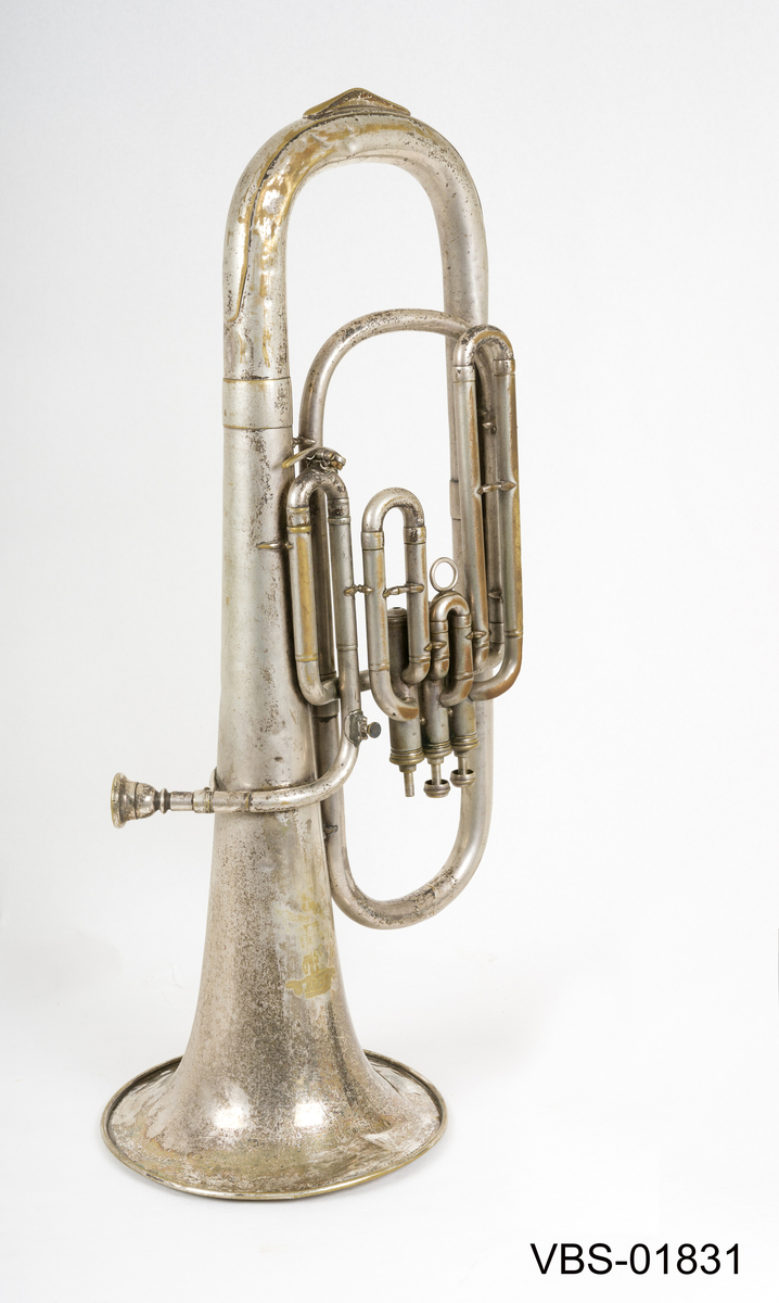 Blåseinstrument i forsølvning messing med tre ventiler. 
Tubaen har et etui tilpasset formen, med et håndtak. Instrument etuiet er foret på innsiden med et mørkeblått ullbelegg, og dekket utenpå med svart kunstlær.