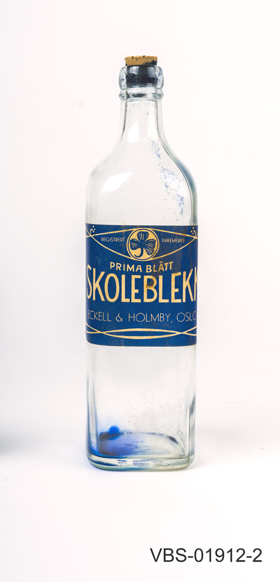 Glassflaske for skoleblekk. Firkantet gejnnomsiktig flaske med kork. 
Stor etikett på 3 sider, tekst på norsk.