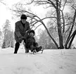 Ett barn och en man leker med en snöspark