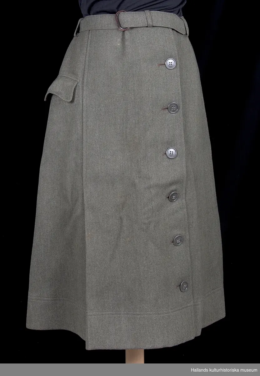 Uniform m/1942 kv. för sjuksköterska.

a) Dubbelknäppt uniformsjacka av grågrön kypertvävd ylle, fodrad med brungrått satintyg. Försedd med grå knappar i syntetmaterial. Krage med slag. Två sidofickor samt två bröstfickor. Skärp i midjan av samma tyg som jackan. På vänster arm ett tygmärke med oljelampa av metall (tjänstetecken m/1946 för sjukvårdspersonal). På jackans insida (vid knäppningen) finns etikett: "PUB. PAUL U. BERGSTRÖMS A-B STOCKHOLM". På dess krage: "AND. G. WALLIN. TEL.2692 - HALMSTAD".

b) Kjol. Enkelknäppt uniformskjol av grågrönt kypertvävt ylle med skärp av samma material. Försedd framtill med 6 stycken knappar av syntetmaterial. Ficka på höger sida. Veckad nedtill på höger sida. I linningen en etikett: "PUB. PAUL U. BERGSTRÖMS A-B STOCKHOLM".

c) Fältmössa. Båtmössa av grågrönt kypertvävt ylle. På insidan en etikett: "PUB. PAUL U. BERGSTRÖMS A-B STOCKHOLM".