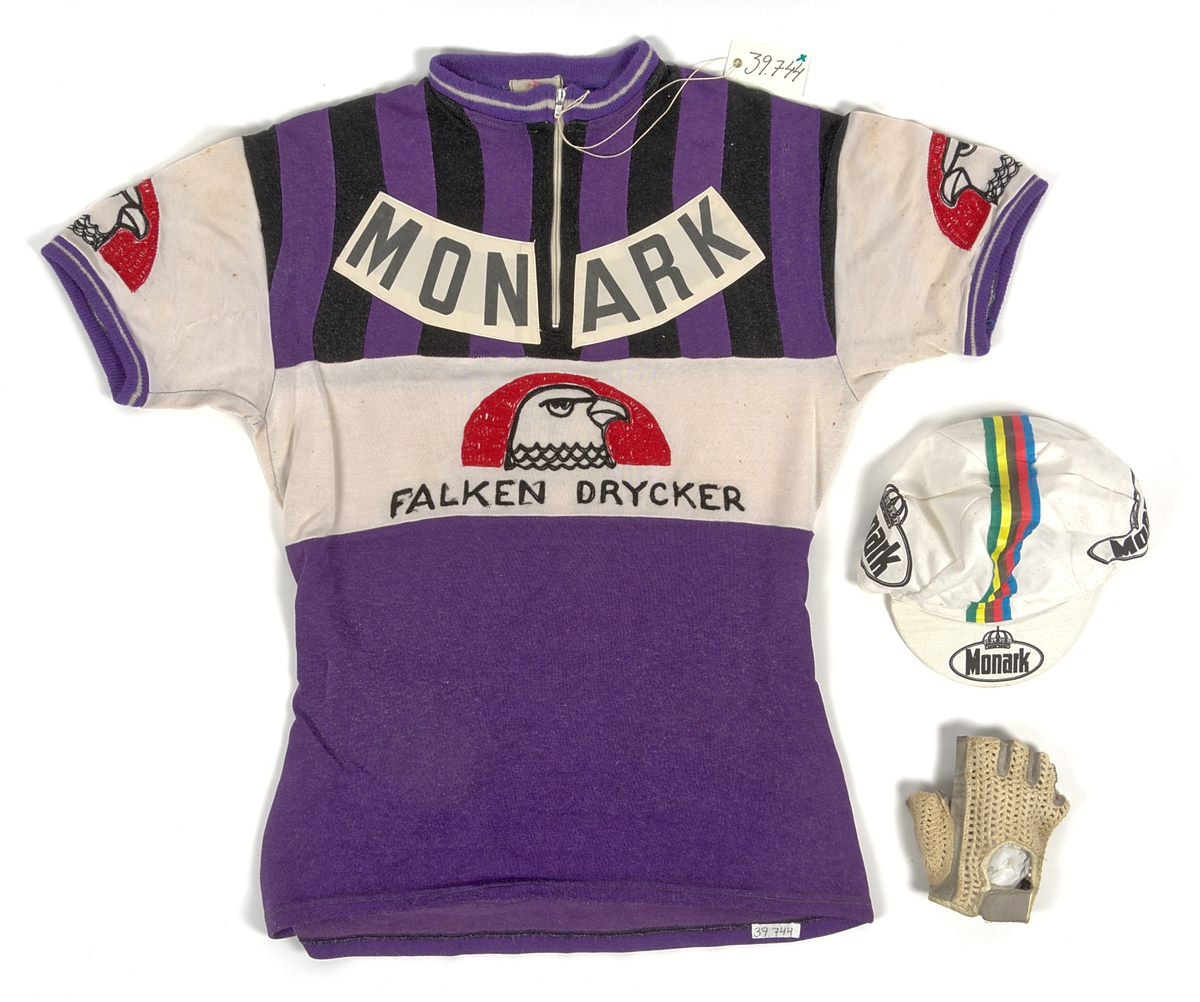 Cykeltröja i vit och lila syntet märkt: "MONARK". Tre fickor på ryggen, märkt: "MONARK" och "FALKEN DRYCKER" på både fram- och baksida. Även "Falkens" logotype på ärmarna.
Med tillhörande monarkkeps och en handske i bakfickor på tröjan.