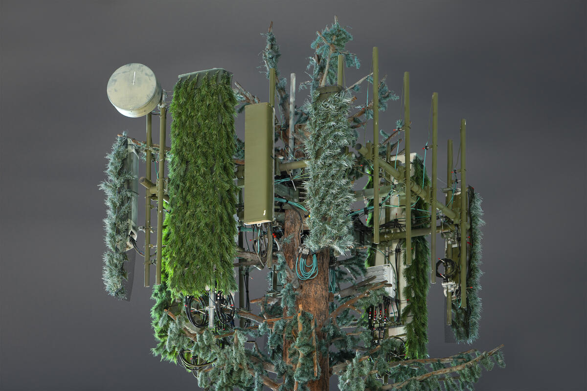 Close-up of a mobile mast that resembles a palm tree, covered with green growths