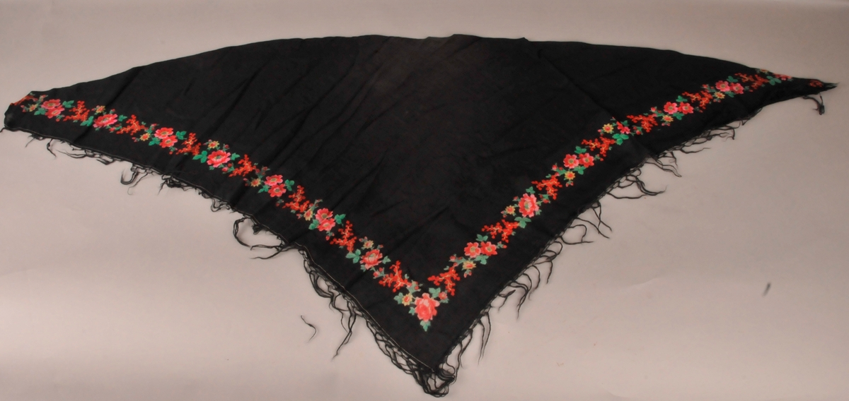 Trekanta tørkle i tynn, svart ull. Tørkledet har trykkt blomstermotiv i friske fargar.Frynser på to av sidene.