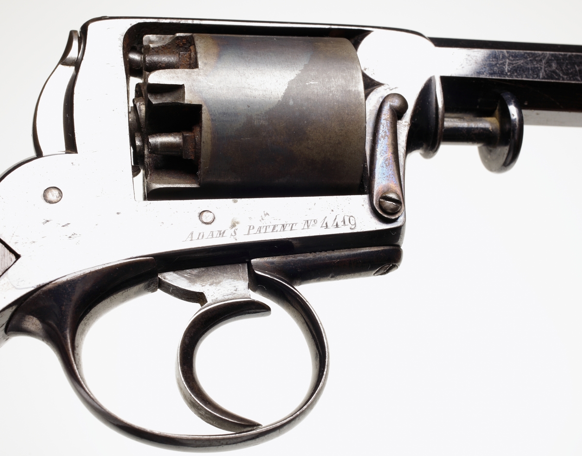 Revolver av slaglåsmodell. Den roterande trumman innehåller plats för fem laddningar. Laddning sker genom att ta loss trumman från stommen. Framför trumman sitter en spärr som trycks in, och sedan kan trumaxeln dras fram och trumman tas ur. En enkel säkring finns vid hanen som aktiveras genom att man trycker löst på avtryckaren, och samtidigt trycks säkringen in så slagstiftet inte kommer åt tändhatten. Avfyrning kan ske endast genom att trycka på avtryckaren, detta då upphakning av hanen ej är möjlig. Hela revolvern är tillverkad av blånerat stål, förutom hanen som är oblånerad. Kolvplattorna är tillverkade av mörkt ädelträ. Stomme och pipa är polerade. På kolvryggen sitter en tumplåt i silver, samt på kolvknappen en liten lucka för tändhattsförvaring. Hela vapnet är odekorerat, och pipan är åttakantig och invändigt räfflad i kaliber .54. Stomme och trumma ej nummerriktiga.
Inskrivet i huvudkatalogen 1990.