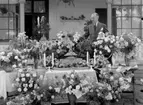 Man omgiven av blomsterarrangemang.
Fotografens ant: Maskininspektör Olsson 18/7 1936.