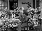 Man omgiven av blomsterarrangemang.
Fotografens ant: Maskininspektör Olsson 18/7 1936.