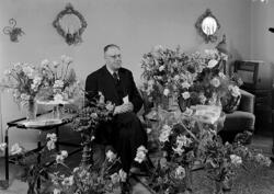 Man omgiven av blommor i hemmiljö.
Fotografens ant: Stations