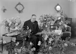 Man omgiven av blommor i hemmiljö.
Fotografens ant: Stations