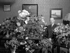 Man i hemmiljö omgiven av blommor.
Fotografens ant: Oscar Stark 50 års dag. 1935.