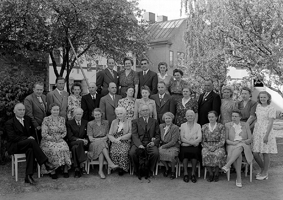 Större grupp män och kvinnor samlade utomhus. Eventuellt släktträff.
Fotografens ant: Paul Larsson.