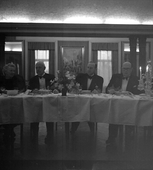 Tre män och en kvinna vid bord.
Fotografens ant:Branzells.