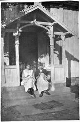 To kvinner sitter ute på trappa og syr duker