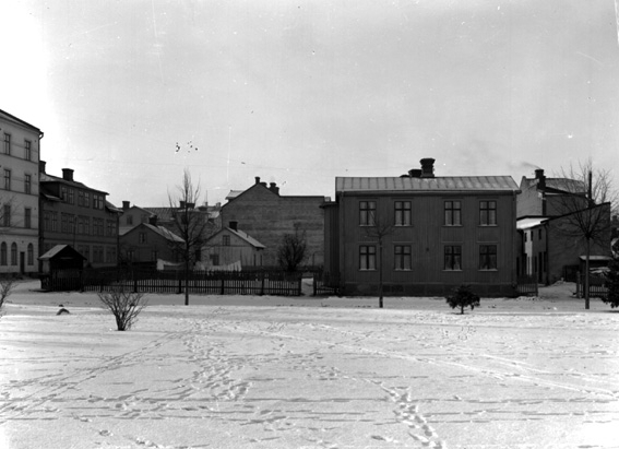 Öppen plats med hus i bakgrunden.