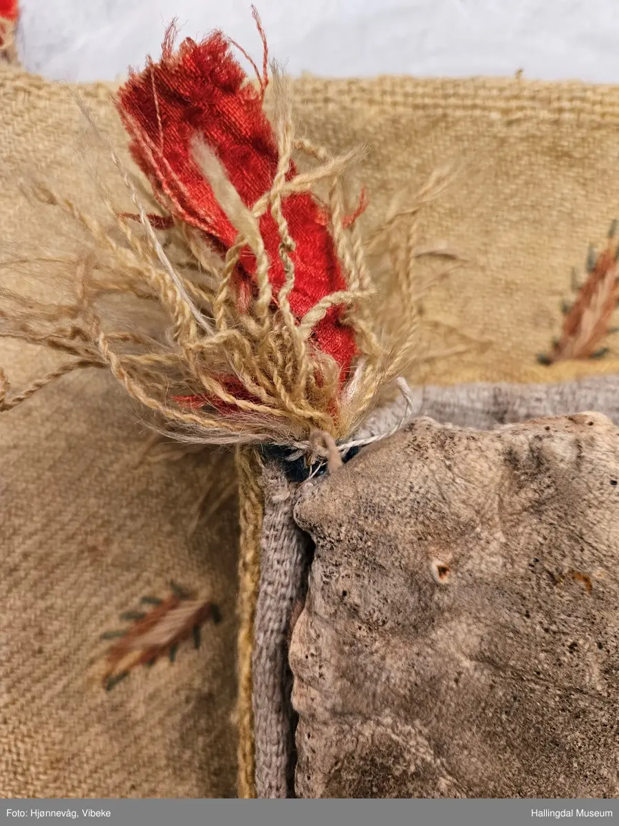 Oversiden er av tykt gult ullstoff, kypertbinding med ullgarnsbroderier. Motivet er en blomsterbukett i en "vase" midt på puta, i hvert hjørne er brodert en stor blomst med stilken ut mot hjørnet og blomsten vendt inn mot midten, alle fire blomstene er like. Midt på puta øverst er det brodert en løve med krone som står på en kvist i halvsirkel med 3 blader. Nederst midt på puta er det brodert 2 "reinsdyr" som står på hver sin "hellebard" med hodet vendt mot hverandre. Under blomstervasen er det brodert: "*1*7*7*8* *H*O*S*"
På hver side av blomstervasen er det brodert en påfugl som ser inn mot midten.  
Baksiden av puta er lagd av skinn med pelsen inn og det garvete skinnet ut. Hvilke dyr skinnet er fra er usikkert, men det er ikke sau. Pelsen er brun og hvit. Mellom skinnet og det gule ullstoffet er det et lag med grovt lintøy i "fiskebeinsmønster". I to av hjørnene er det trafs laget av ullgarn og remser med tøy av rød ulldamask. Broderiet er slitt og falmet.