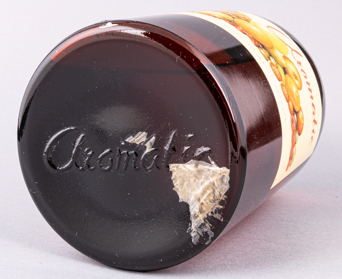 Glasflaska, brun, med skruvkork. Innehåller essens. Etikett: "Aromatic 1 kg Ahlgrens Tekniska special" samt frukter.