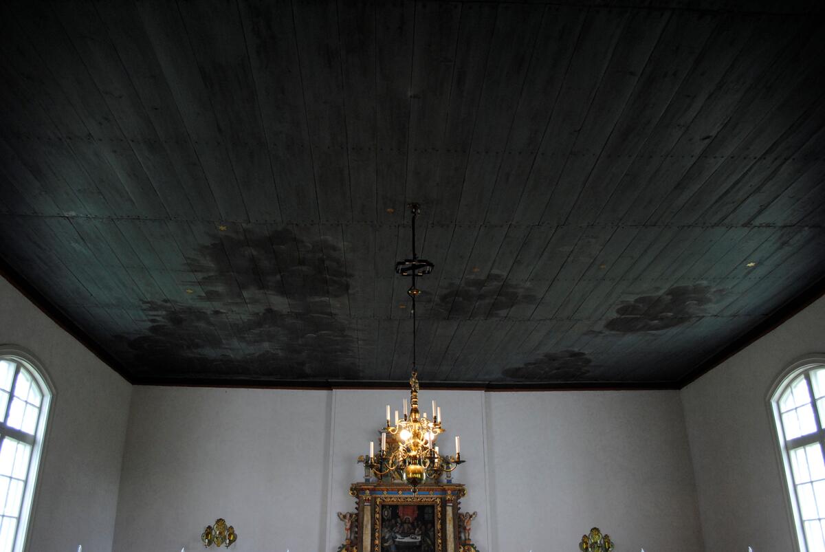 Interiör i Laxarby kyrka. Altaruppsatsen är från 1769 och centralmotivet består av en så kallad kalvariegrupp med Kristus på korset omgiven av Maria och aposteln Johannes. Uppsatsen, liksom predikstolen från 1747, två änglar med psalmnummertavlor från 1767, och en timglasängel, är alla utförda av den i stiftet välkände bildsnidaren Isak Schullström. Taket dekorerades 1777 med moln och stjärnor av kyrkomålaren Carl Zetterström.