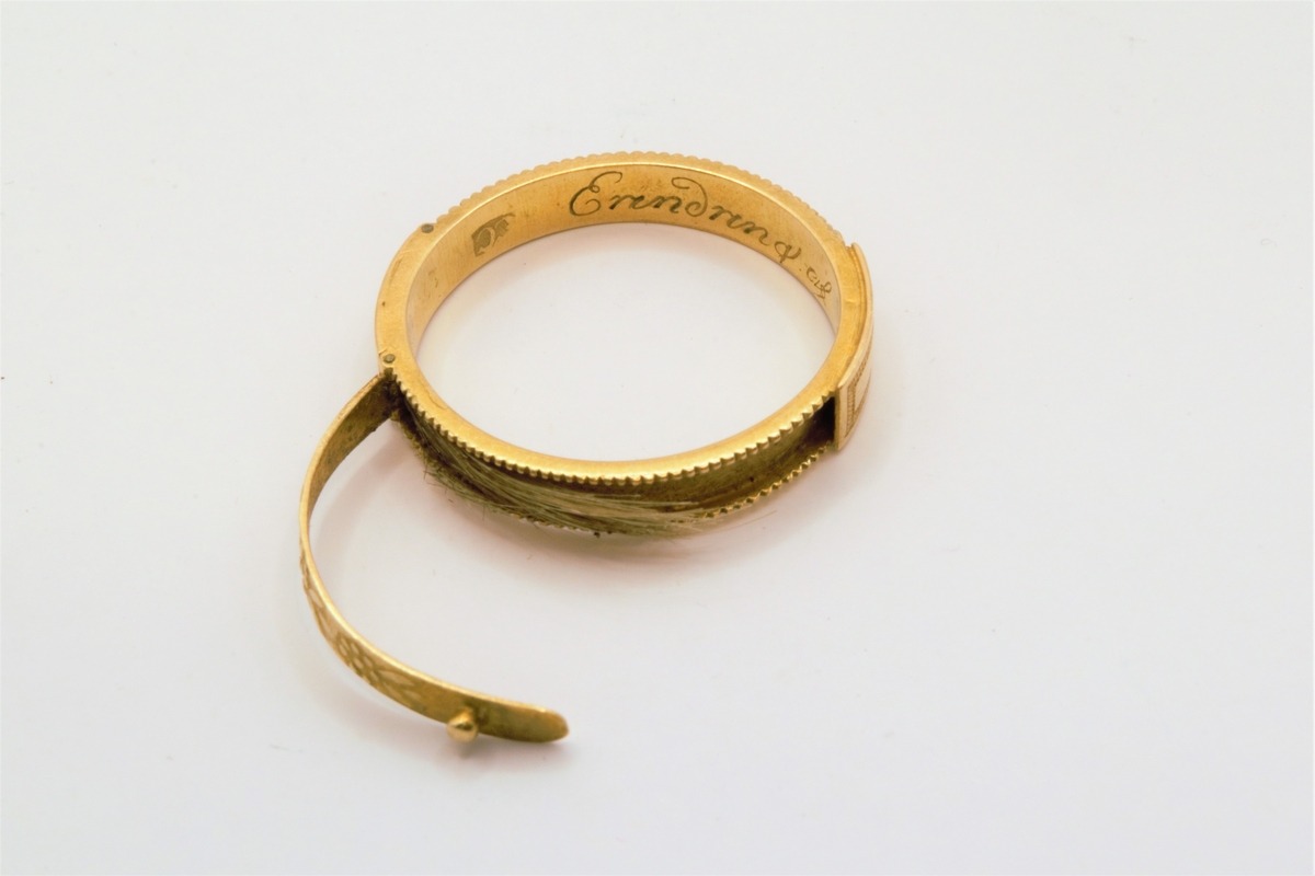 På oversiden er det to 2-cm lange lokk/avlukker med dobbelbunn. Lokkene er hengslet og forsynt med en liten knott til håndtak. Inne i den ene av avlukkene ligger en hårlokk. Begge lokkene har forsiringer av små blomster og blader.