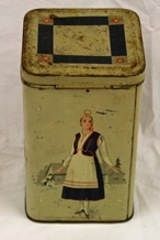 Boks. Metall. 4-sidet med kvadratisk bunn og topp. Påhengslet lokk. Beigemalt med bunadkledt dame på hver langside. Geometrisk ornamentikk på lokket. Blank metall innvendig.