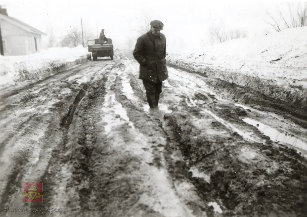 Vårløsning på E18 ca. 100 meter syd for Haugtuft Landhandel i Sem (nå Tønsberg)  10. april 1937.  Dårlig vedlikeholdt grusveg.
På bildet  oppsynsmann Peder Berg.