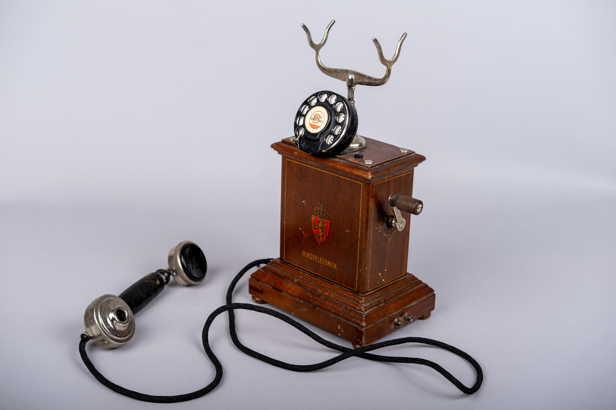 Rikstelefonenns bordtelefon fra 1918.
Telefonen består av telefonrør, telefon med tallskive, kabel og ledning. 
Tallskivet har tall 0-9.
Sveiv på høyre siden.  
På front siden riksvåpen med løven og kkronen, under det "RIKSTELEFON"-