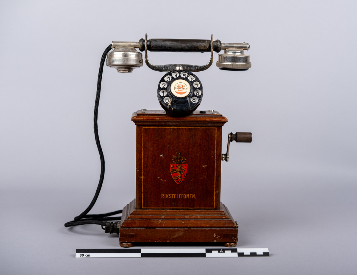 Rikstelefonenns bordtelefon fra 1918.
Telefonen består av telefonrør, telefon med tallskive, kabel og ledning. 
Tallskivet har tall 0-9.
Sveiv på høyre siden.  
På front siden riksvåpen med løven og kkronen, under det "RIKSTELEFON"-