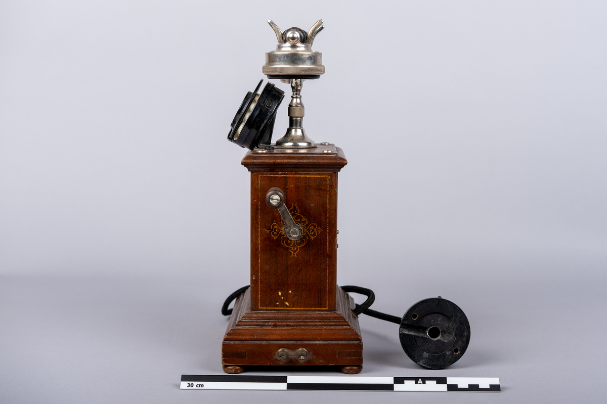 Rikstelefonenns bordtelefon fra 1918.
Telefonen består av telefonrør, telefon med tallskive, kabel og ledning. 
Tallskivet har tall 0-9.
Sveiv på høyre siden.  
På front siden riksvåpen med løven og kkronen, under det "RIKSTELEFON"-