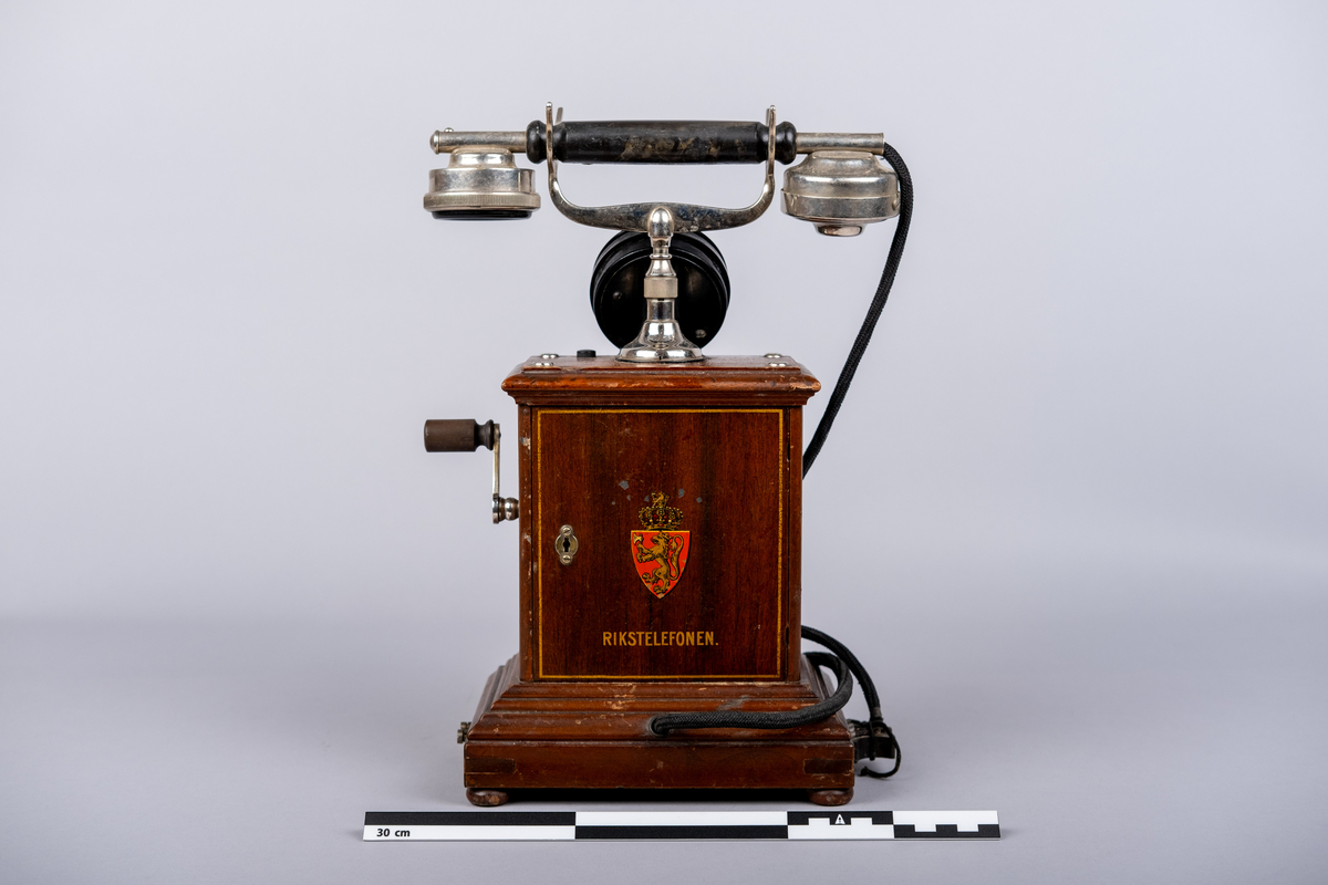 Rikstelefonenns bordtelefon fra 1918.
Telefonen består av telefonrør, telefon med tallskive, kabel og ledning. 
Tallskivet har tall 0-9.
Sveiv på høyre siden.  
På front siden riksvåpen med løven og kkronen, under det "RIKSTELEFON"-