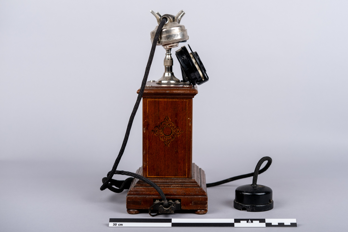 Rikstelefonenns bordtelefon fra 1918.
Telefonen består av telefonrør, telefon med tallskive, kabel og ledning. 
Tallskivet har tall 0-9.
Sveiv på høyre siden.  
På front siden riksvåpen med løven og kkronen, under det "RIKSTELEFON"-