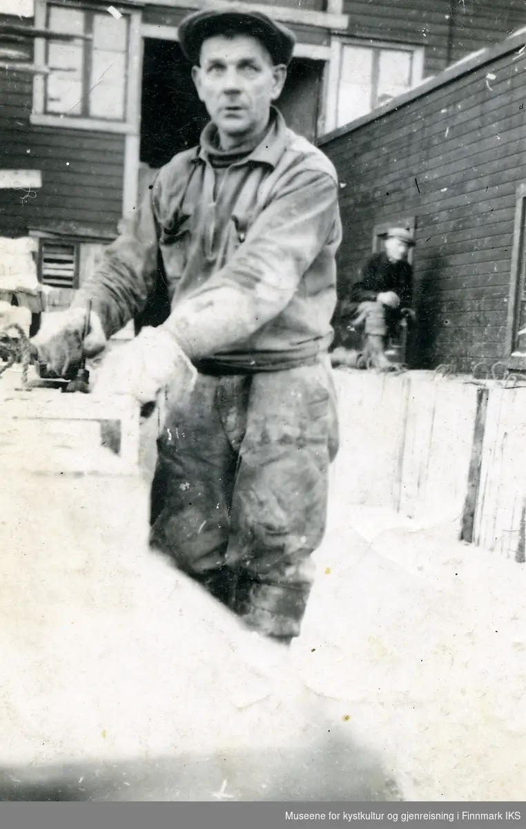 Honningsvåg. Alfred Thorstensen merker fiskekasser på Eldebruket. I bakgrunnen kaiformann Olaf Løkke. Ca. 1938/39.