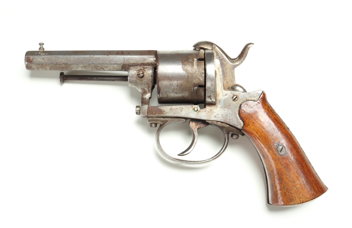 Revolver av så kallad Lefaucheuxtyp i stål med kolvplattor i trä, och plats för sex stiftantändningspatroner i trumman. Laddning sker genom att laddluckan på höger sida om trumman fälls upp, och därefter patroner förs in i patronläget. Framtill på höger sida finns en utstötare för de avlossade patronhylsorna. På pipan vid mynningen sitter ett stolpkorn. Revolvern är märkt med två kronor och ett "U" på trumman och höger sida ovanför varbygeln.
Inskrivet i huvudkatalogen 1974.