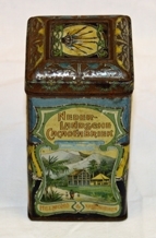 Boks. Rektangulær. Kvadratisk bunn/topp. Metall. Påhengslet lokk. Lokket er avrundet mot topp med 4-kant i relieff. Illustrasjoner av dronning, landskap og logo.  Noe rusten. Inneholder knapper.