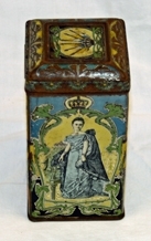 Boks. Rektangulær. Kvadratisk bunn/topp. Metall. Påhengslet lokk. Lokket er avrundet mot topp med 4-kant i relieff. Illustrasjoner av dronning, landskap og logo.  Noe rusten. Inneholder knapper.