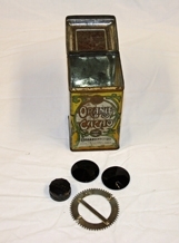 Boks. Rektangulær. Kvadratisk bunn/topp. Metall. Påhengslet lokk. Lokket er avrundet mot topp med 4-kant i relieff. Illustrasjoner av dronning, landskap og logo.  Noe rusten. Inneholder knapper.