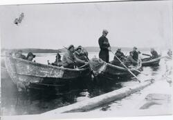 Tømmerfløting i Øvre Pasvik. Flere personer arbeider i båter