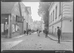 Platensgatan i Linköping. Korsningen med Ågatan. Man ser en pojke blicka mot kameran. Vy mot Stora torget. Skyltning. 
Bilder från gatuhörn i staden Linköping åren 1909 till 1913. Bilderna är tagna i centrala Linköping i ett projekt att dokumentera Linköping för Linköpings stad.