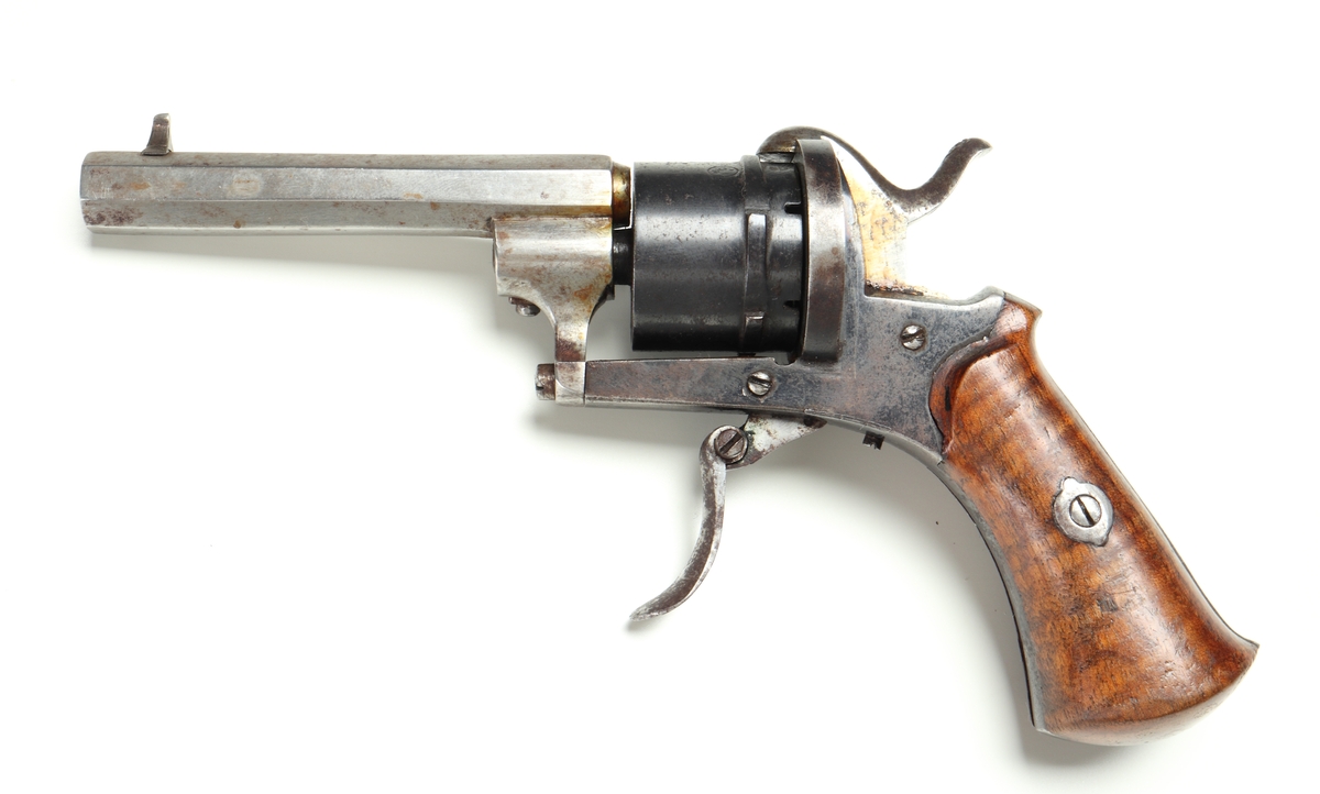 Revolver av så kallad Lefaucheuxtyp i stål med kolvplattor i trä, och plats för sex stiftantändningspatroner i trumman. Pipa i stål, kolv av brunbetsat trä, utan varbygel, samt med fällbar avtryckare. Trumman och sidoblecken blånerade. På pipan, vid mynningen, sitter ett stolpkorn i mässing. Laddning sker genom att laddluckan på höger sida om trumman fälls upp, och därefter patroner förs in i kamrarna. Framtill, på höger sida, finns en utstötare för de avlossade patronhylsorna. Revolvern är märkt med en krona och ett "U" på trumman och höger sida under utstötarstångens fäste, samt även "LIG" inom oval på trumman.
Inskrivet i huvudkatalogen 1947.