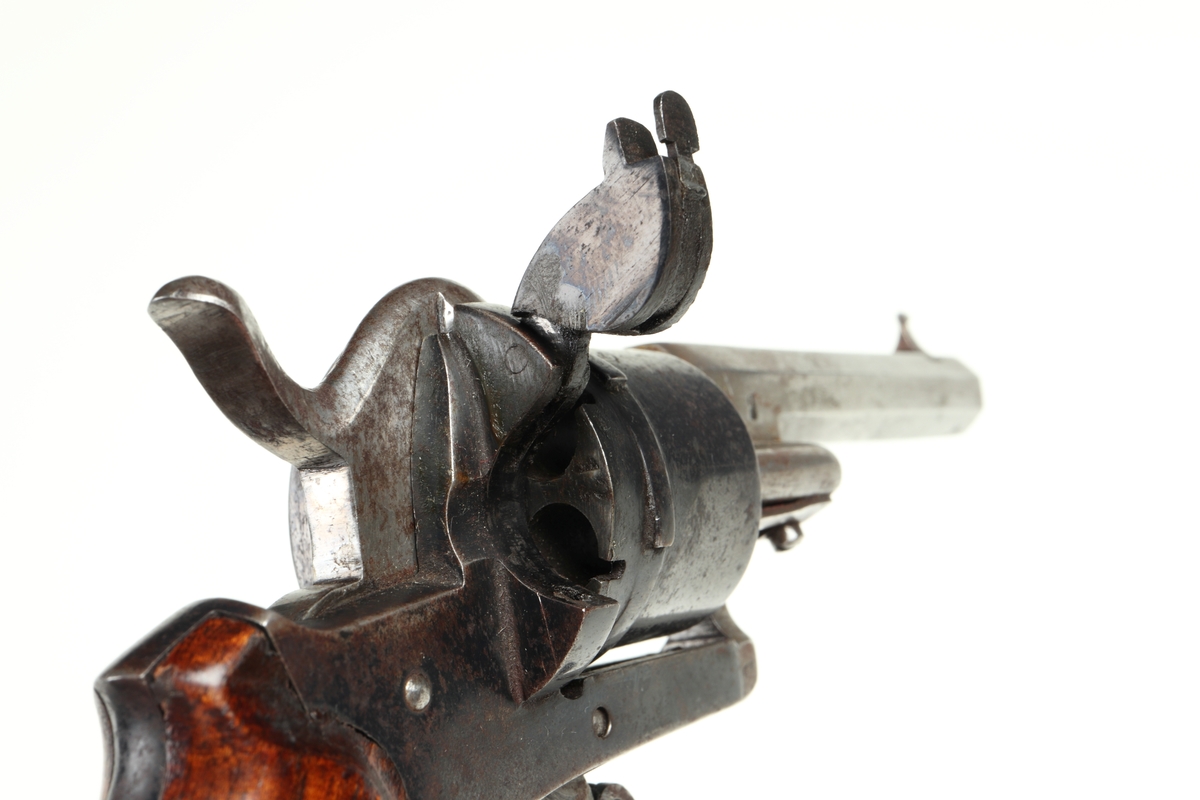 Revolver av så kallad Lefaucheuxtyp i stål med kolvplattor i trä, och plats för sex stiftantändningspatroner i trumman. Pipa i stål, kolv av brunbetsat trä, utan varbygel, samt med fällbar avtryckare. Trumman och sidoblecken blånerade. På pipan, vid mynningen, sitter ett stolpkorn i mässing. Laddning sker genom att laddluckan på höger sida om trumman fälls upp, och därefter patroner förs in i kamrarna. Framtill, på höger sida, finns en utstötare för de avlossade patronhylsorna. Revolvern är märkt med en krona och ett "U" på trumman och höger sida under utstötarstångens fäste, samt även "LIG" inom oval på trumman.
Inskrivet i huvudkatalogen 1947.