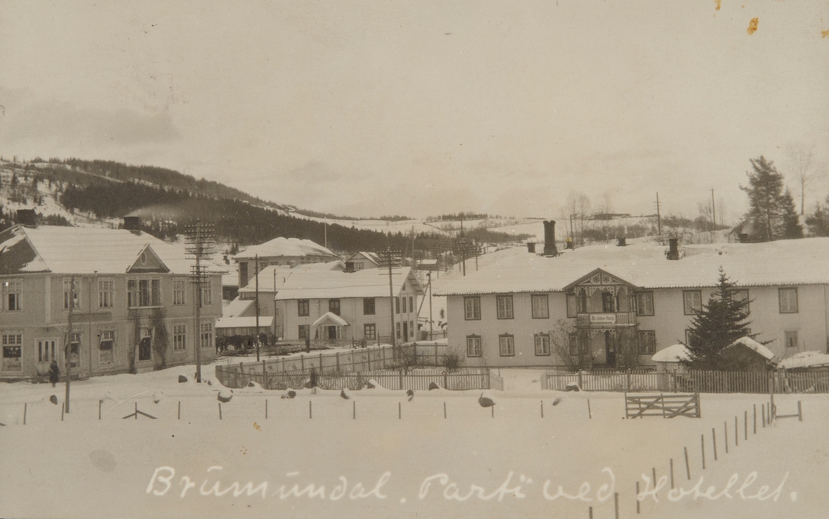 Postkort, Ringsaker, Brumunddal Furnesvegen, fra venstre Helgeby med Kooperativen oppført 1913, Stampen, Brumunddal hotell i Øverbakken til høyre, vinter,