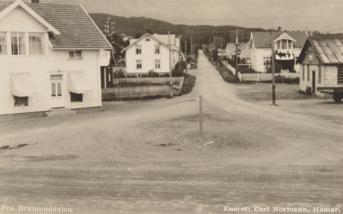 Postkort, Ringsaker, Brumunddal, i krysset Ringsakervegen - Berger Langmoens veg, Stensgård, Sandheim, Bro Mekaniske verksted. Huset til venstre: Hanna Økelsrud bygde sin gård i 1920. Kjøpmann Ole Hole eide huset da bildet ble tatt. Senere Aage Thomassen.