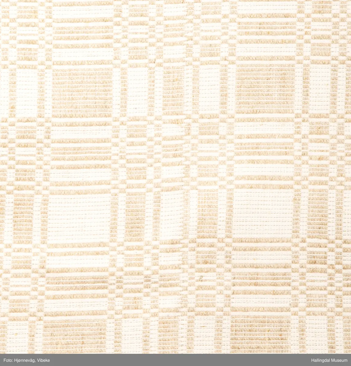 Linduk, linrenning og lin i innslag, beige. Danner ruter ig striper, tavlebragd. Duken er vevd i to lengder som er sydd sammen på midten med håndsøm.